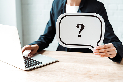 cropped view of woman holding speech bubble with question mark while working in office