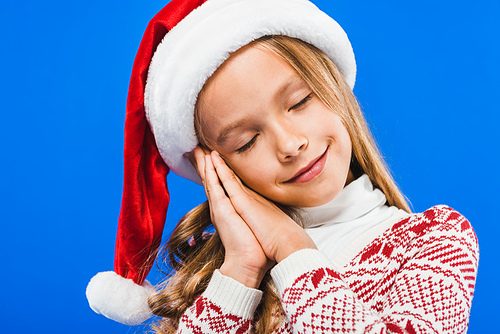 cute kid in santa hat and sweater sleeping isolated on blue