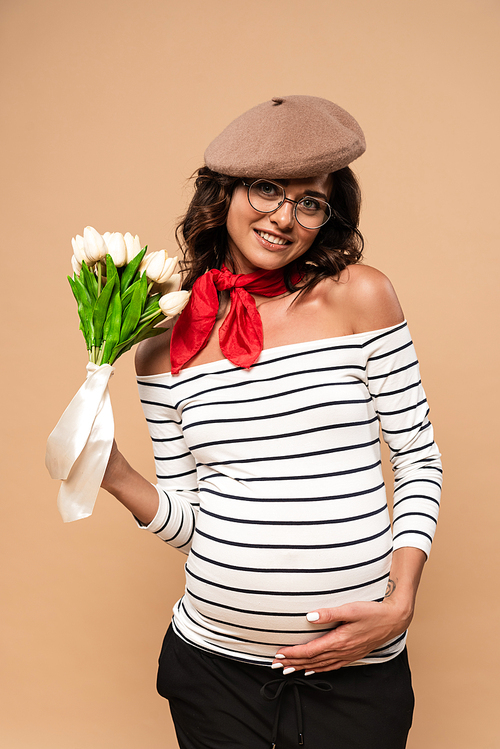 pregnant french woman in beret holding bouquet on beige background