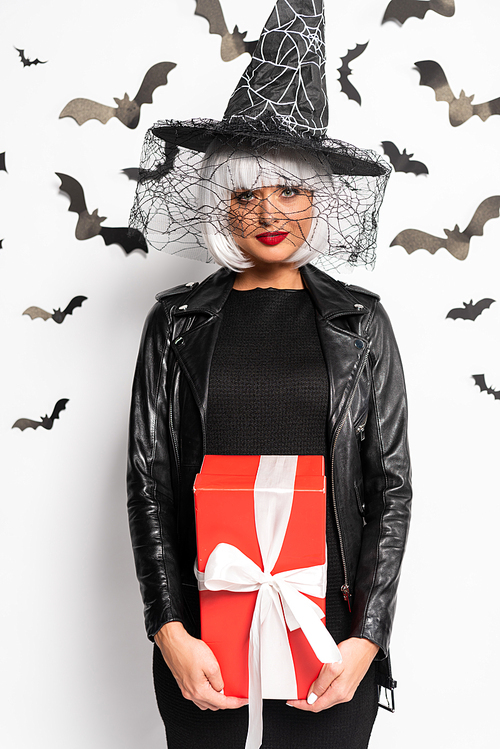 attractive woman in witch hat and wig holding gift in Halloween