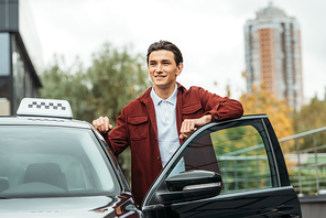 Smiling taxi driver beside open car door