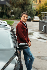 Smiling taxi driver  beside car