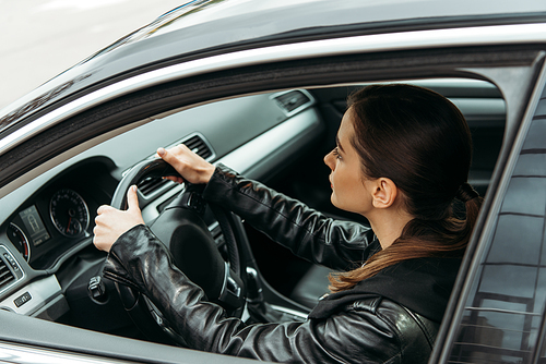 Side view of female taxi driver holding steering wheel