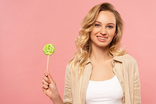 Smiling woman with dental braces holding lollipop isolated on pink