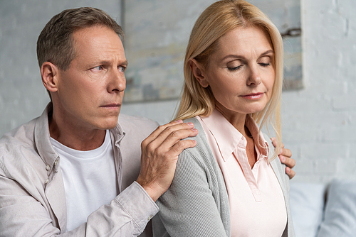 Man calming down worried wife at home