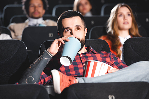 selective focus of handsome man drinking soda and watching movie in cinema