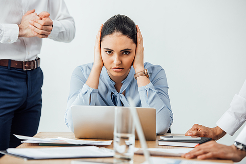 Selective focus of mexican businesswoman covering ears near multiethnic colleagues in office