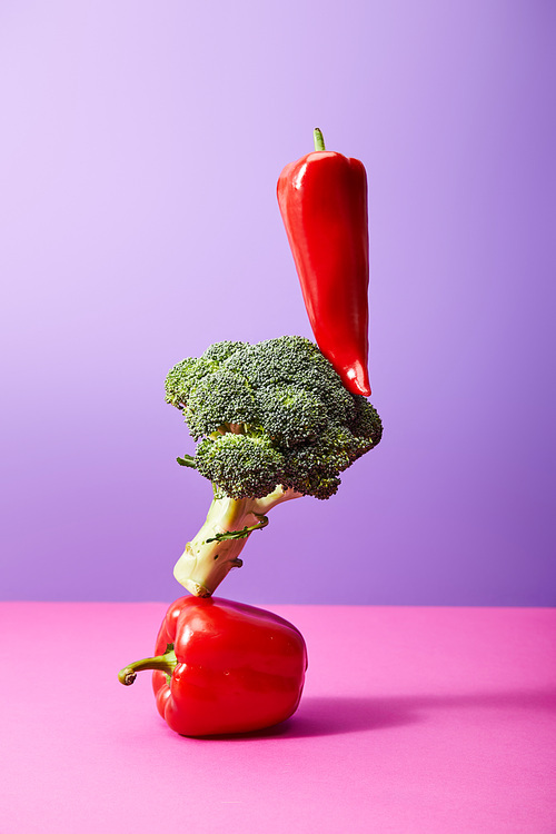 fresh chili pepper on broccoli and bell pepper on purple and pink