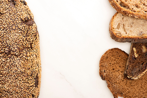 top view of fresh whole grain bread slices and loaf on white background with copy space