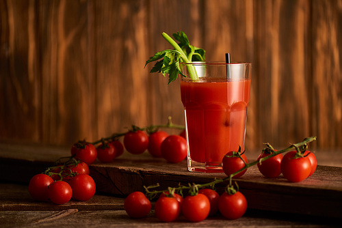 selective focus of bloody mary cocktail in glass on wooden background with tomatoes