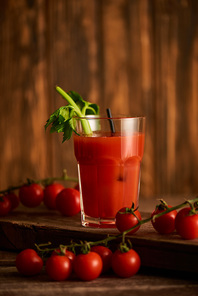 selective focus of bloody mary cocktail in glass on wooden background with tomatoes