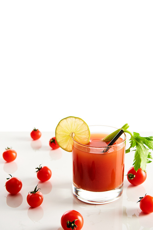bloody mary cocktail in glass garnished with lime and celery isolated on white with tomatoes