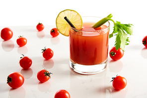 bloody mary cocktail in glass garnished with lime and celery isolated on white with tomatoes