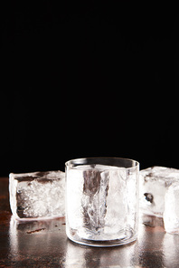 glass near ice cubes isolated on black