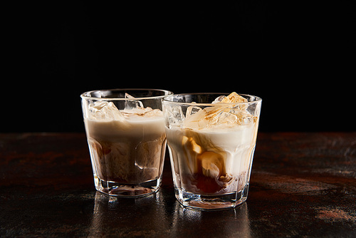 white russian cocktail in glasses with ice cubes isolated on black