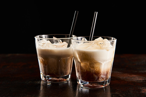 fresh white russian cocktail in glasses with straws isolated on black