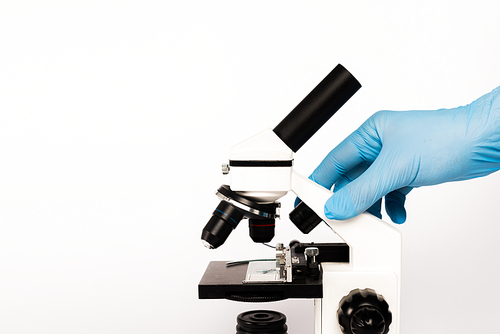 cropped view of scientist in latex glove touching microscope isolated on white