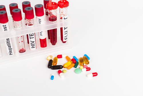 test tubes with blood samples and lettering near pills isolated on white