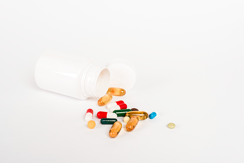 bottle near colorful pills on white with copy space