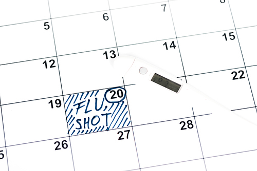 digital thermometer on calendar with marked date and flu shot lettering