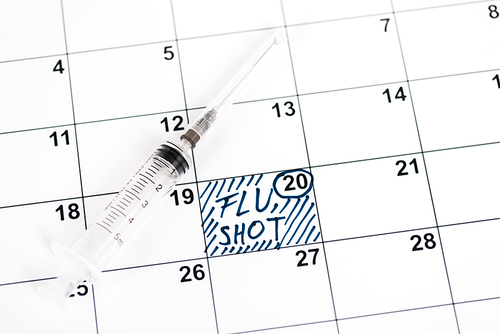 syringe on calendar with marked date and flu shot lettering