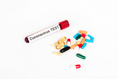 colorful pills near sample with coronavirus test lettering isolated on white
