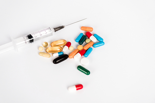 colorful pills near syringe on white with copy space