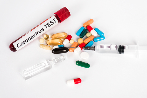 colorful pills near sample with coronavirus test lettering and syringe on white