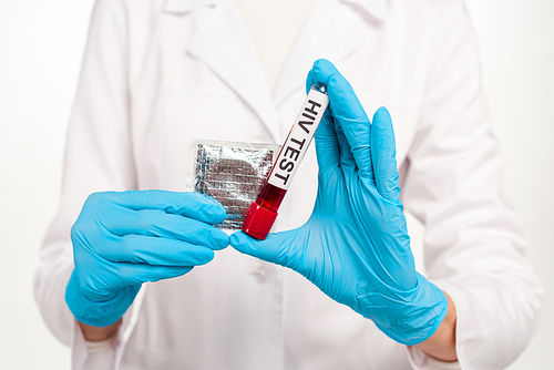 cropped view of scientist in latex gloves holding sample with hiv test lettering and condom isolated on white