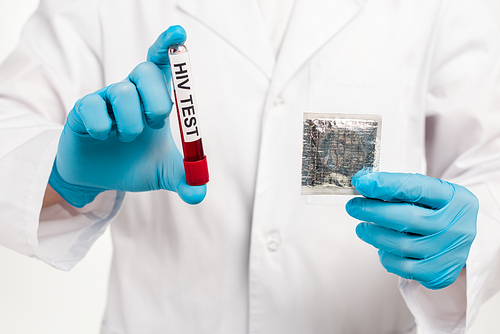 cropped view of scientist holding sample with hiv test lettering and condom isolated on white