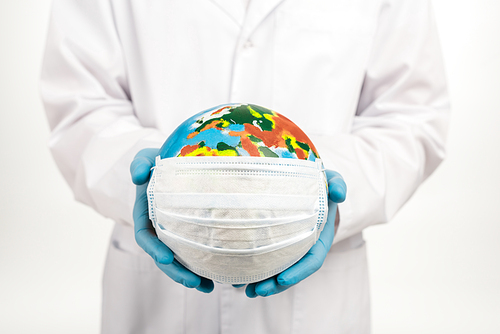 cropped view of scientist holding globe in protective mask isolated on white