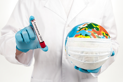 cropped view of scientist holding globe in protective mask and sample with coronavirus test lettering isolated on white