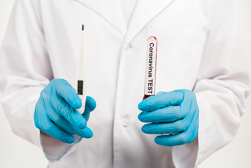 cropped view of scientist holding sample with coronavirus test lettering and digital thermometer isolated on white