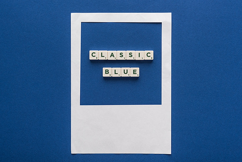 top view of classic blue lettering on cubes in white photo frame on blue background