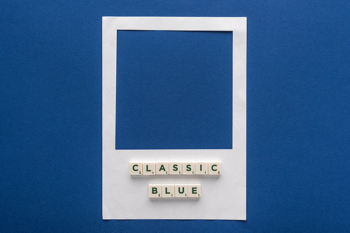 top view of classic blue lettering on cubes on white photo frame on blue background