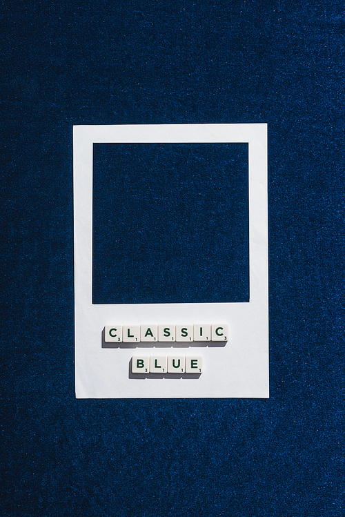 top view of classic blue lettering on cubes and white photo frame textured blue background