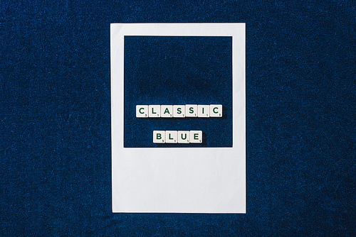 top view of classic blue lettering on cubes and white photo frame on textured blue background
