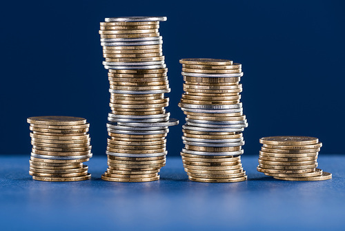 stacks of metal silver and golden coins on blue background