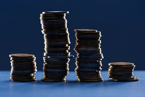 stacks of metal coins in shadow on blue background