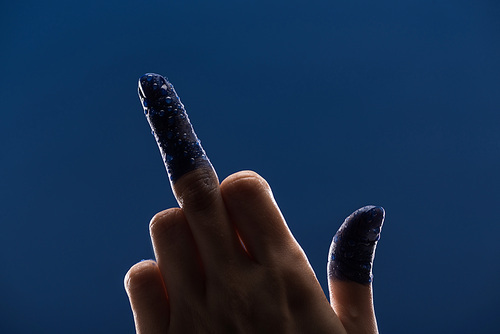 cropped view of female hand with wet painted fingers showing middle finger isolated on blue