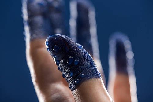 close up view of female hand with wet painted fingers isolated on blue