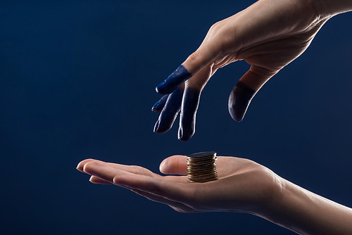 cropped view of female hand with painted fingers holding coins isolated on blue