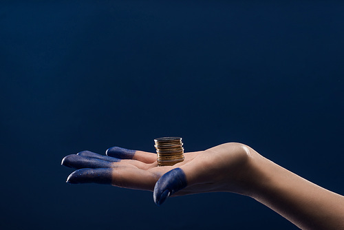 cropped view of female hand with painted fingers holding coins isolated on blue