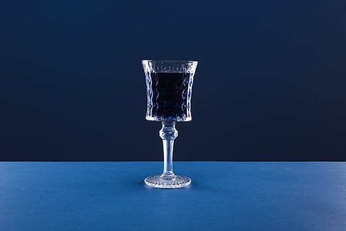 crystal faceted glass with drink isolated on blue