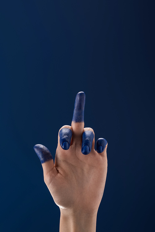 cropped view of female hand with painted fingers showing middle finger isolated on blue