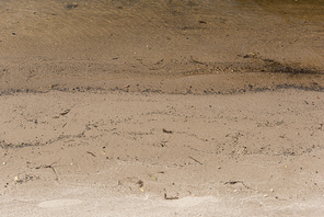 brown textured surface with sand and water with copy space