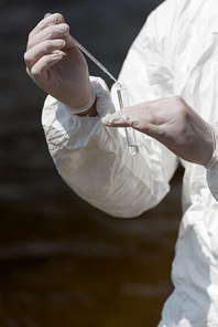 partial view of water inspector in latex gloves with test tube taking water sample