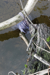 selective focus of plastic bag and lumber in dirty water at river