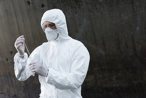 water inspector in protective costume and respirator taking water sample