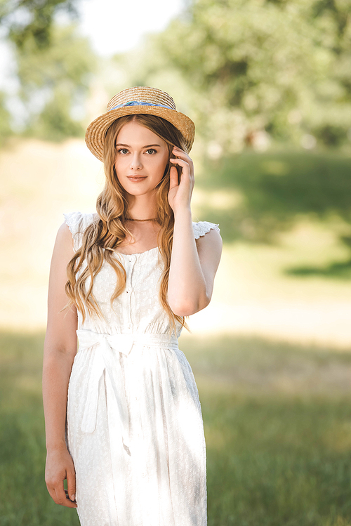 beautiful girl with straw hat standing on meadow and 
